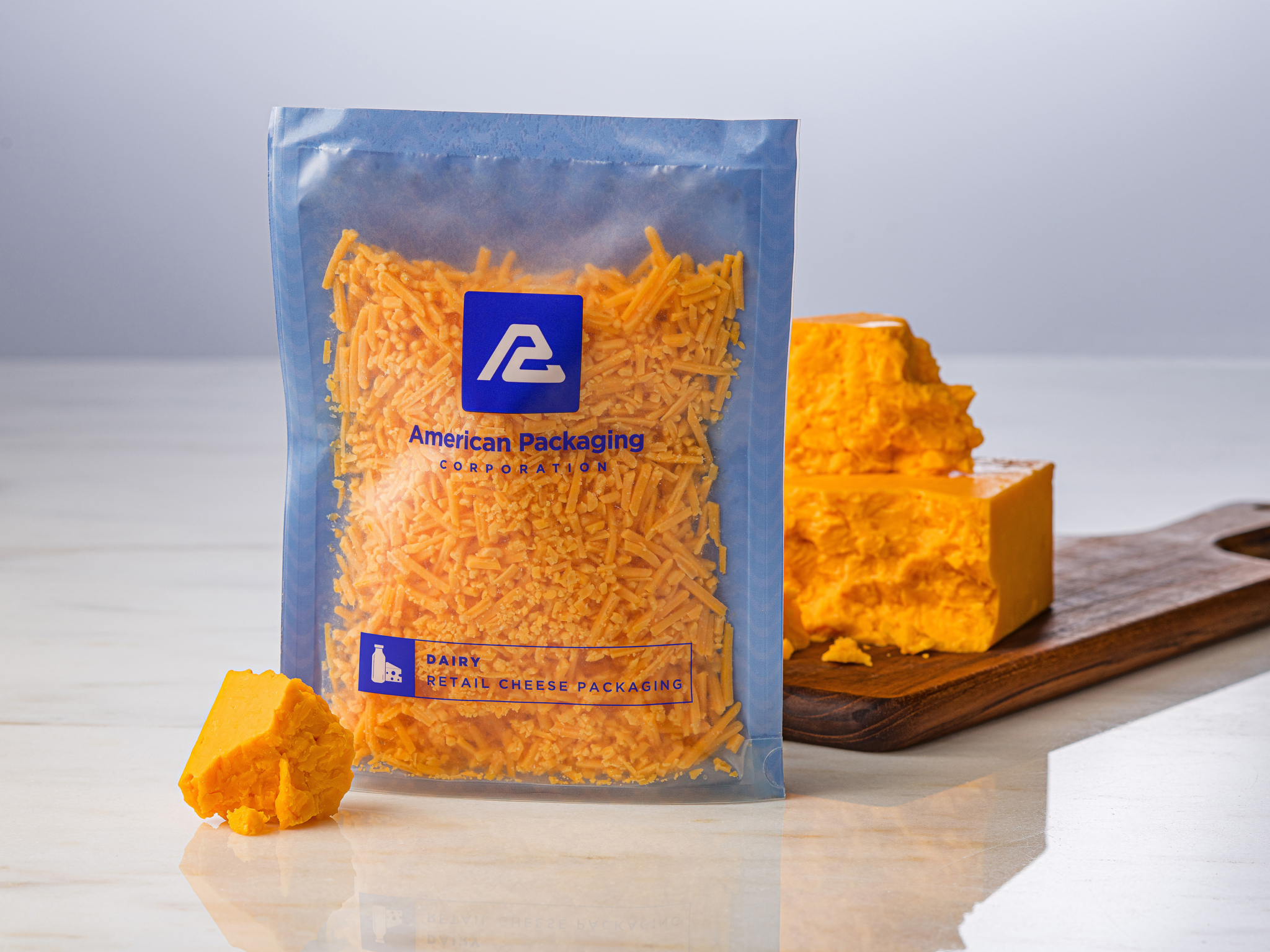 APC's Cheese Package Filled with Cheese and a Block of Cheddar on a Cutting Board